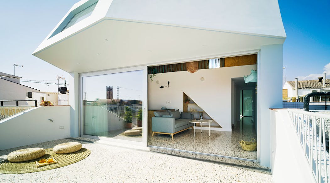 Un sol en terrazzo crée la continuité entre la terrasse et la pièce à vivre d'une maison contemporaine