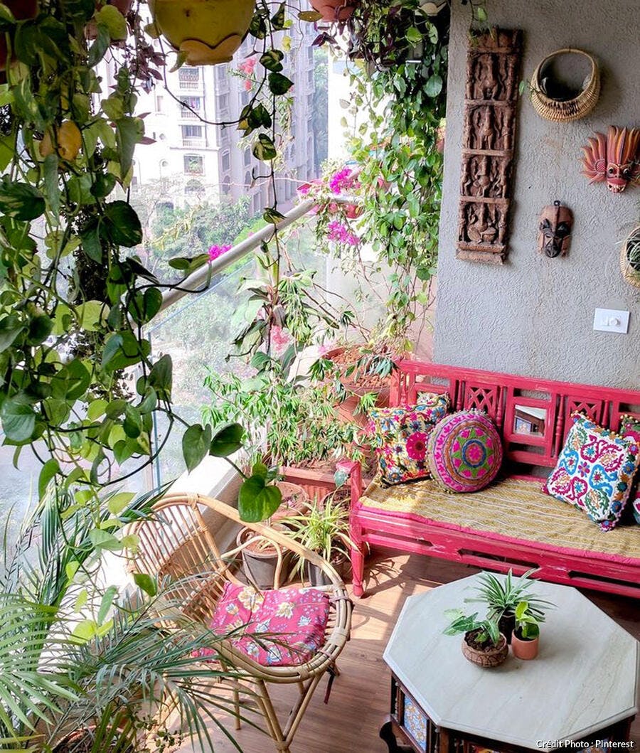 Balcon hippie avec masques africains décoratifs, nombreuses plantes vertes et fauteuil en rotin