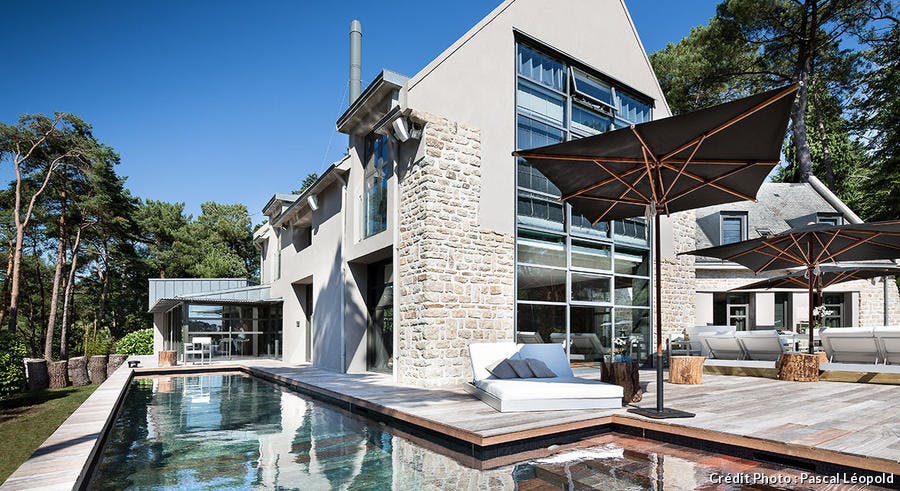 Une piscine en bois face à une maison contemporaine.