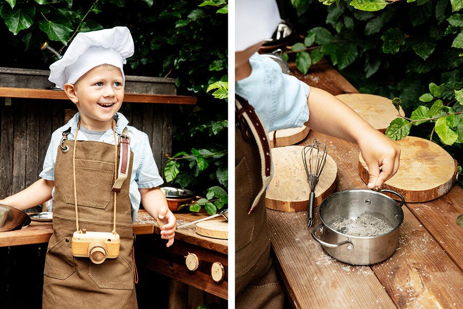 Enfant en tenue de chef qui cuisine au jardin.
