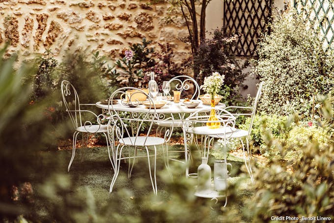 Jardins de l'hôtel luxuriant et table en fer blanc.