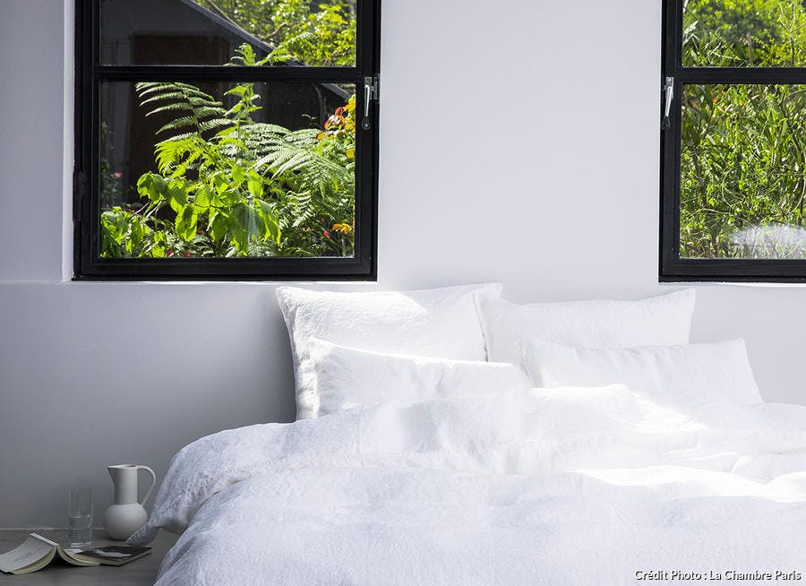une parure de lit en lin lavé blanc dans une chambre avec une fenêtre d'atelier