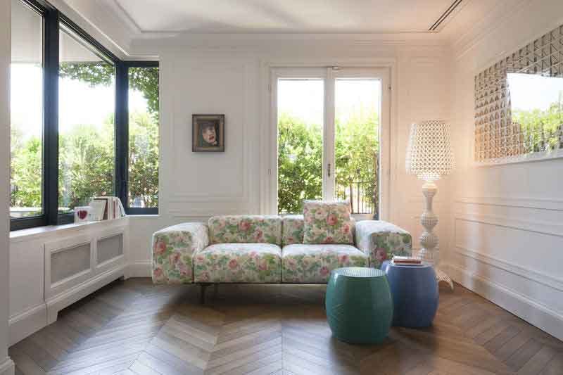 un salon dans une appartement haussmanien avec un canapé fleuri et des touches de couleur.