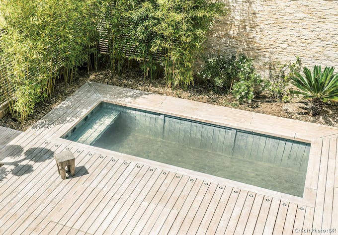 Une piscine ombragée avec une terrasse en bois