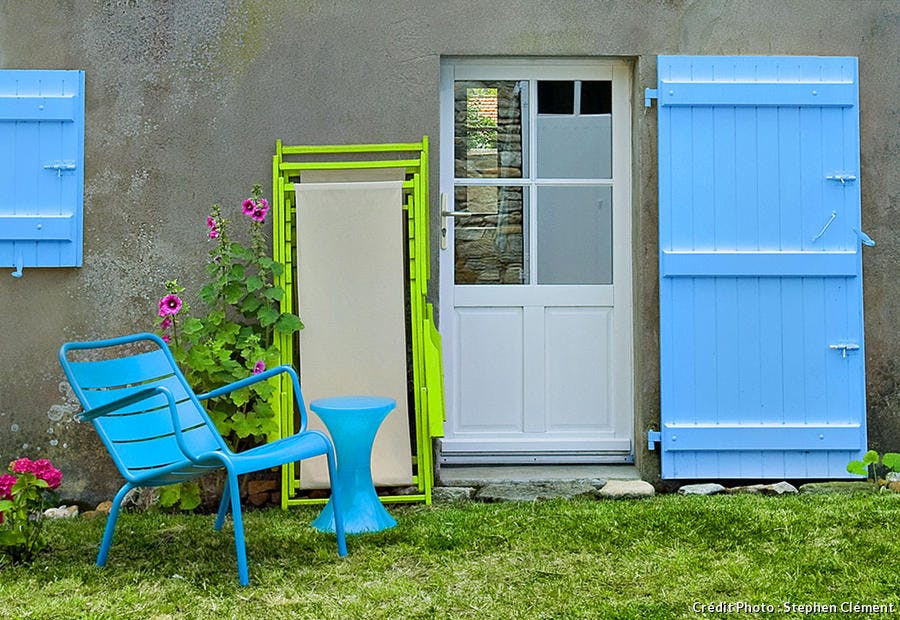 Maison aux volets bleus et mobilier de jardin assorti.