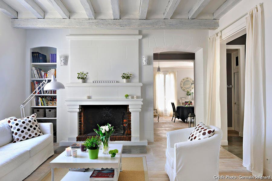 Salon blanc avec cheminée, spacieux et lumineux.