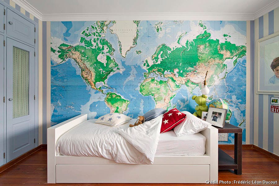 Chambre d'enfant avec planisphère géant en guise de papier peint au dessus du lit.