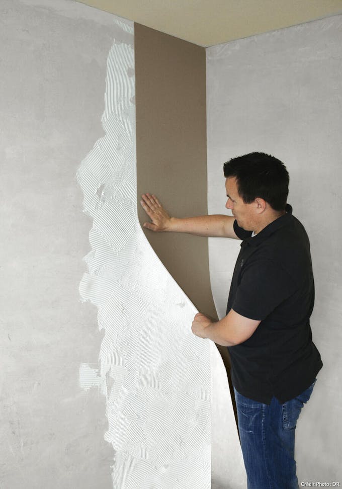 Homme en train de poser un isolant sur un mur pendant des travaux 