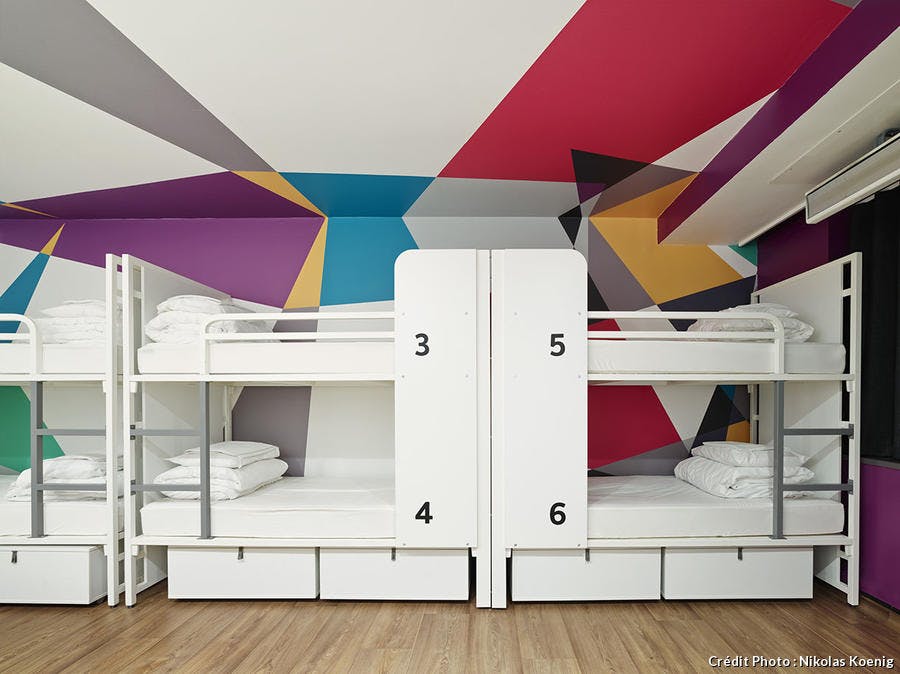 Dortoirs avec lits blancs superposés, plafond et haut des murs peints en couleur avec des perspectives.