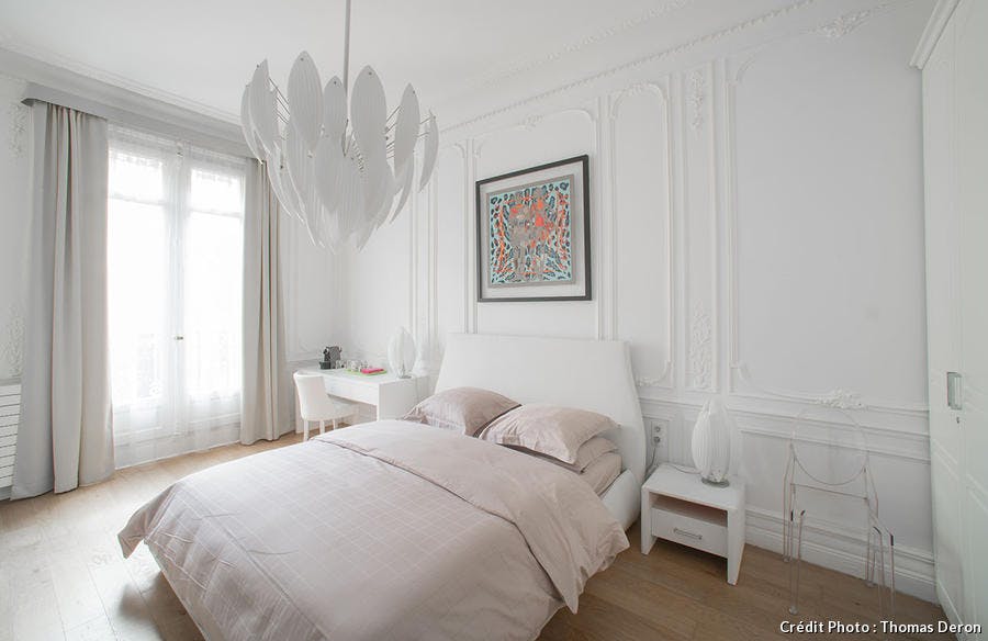 Grande chambre blanche et lumineuse, carré Hermès encadré au-dessus du lit.