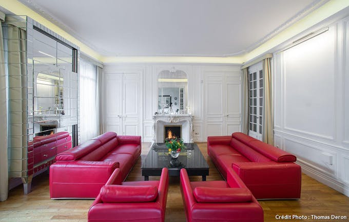 Grand salon blanc à fauteuils et canapés en cuir rouge, meubles en cristal.
