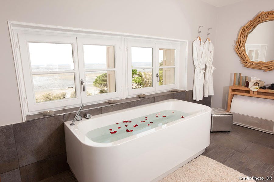 Salle de bains luxueuse, baignoire jacuzzi design donnant sur l'horizon marin.