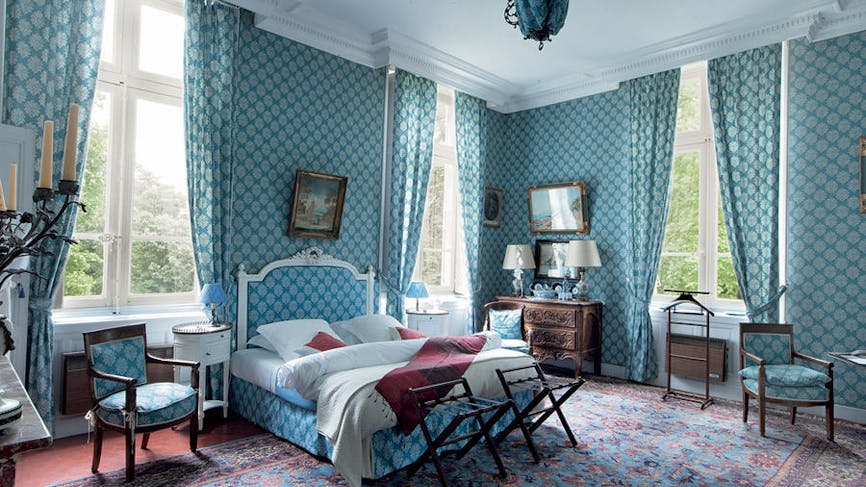 Chambre du château, au style ancien avec des tapisseries. Dominante bleue.