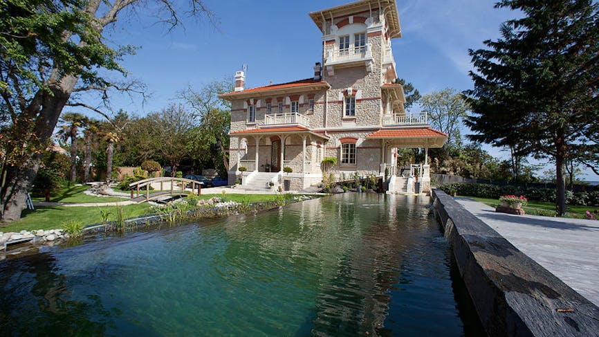 Extérieur de la Villa avec son grand bassin et son petit pont en bois.