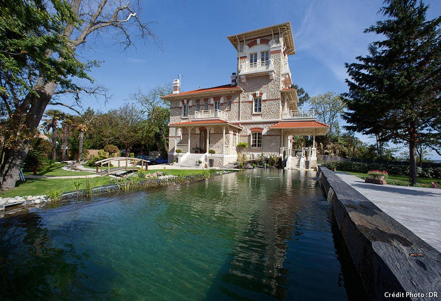 Extérieur de la Villa avec son grand bassin et son petit pont en bois.
