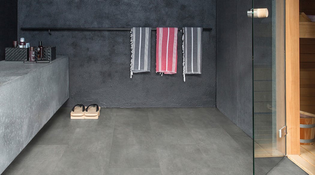 Une salle de bain associant des gris foncés dur les murs, le sol et la baignoire, façon béton ciré.