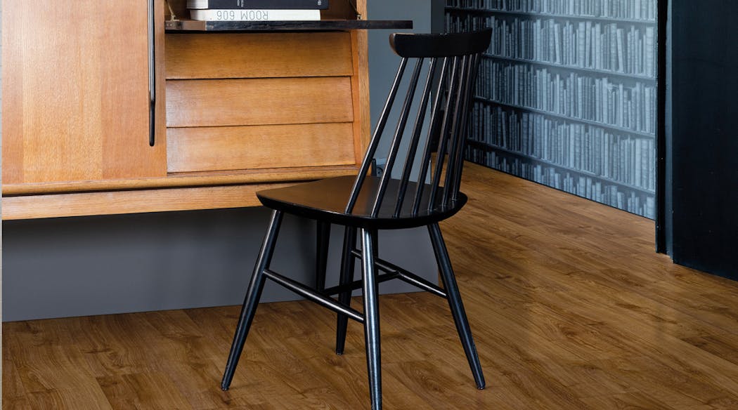 Un bureau avec une chaise noire et un sol imitation parquet en bois marron foncé.