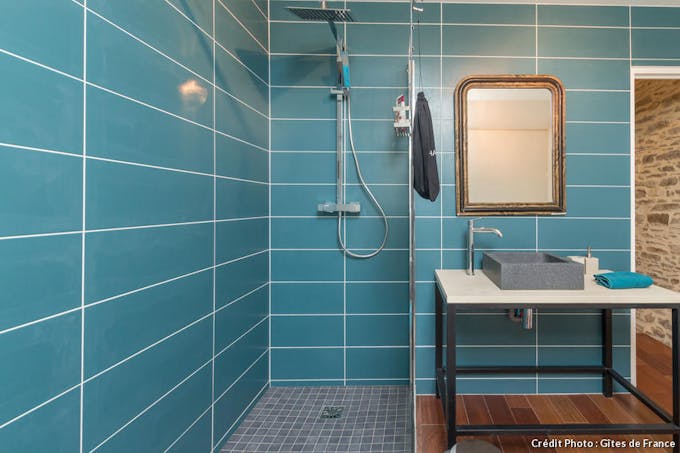 Une salle de bain entièrement tapissée de carreaux bleus turquoise.