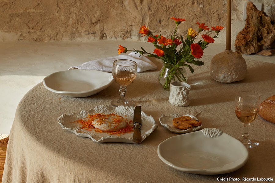 Table dressée sur nappe beige avec fleurs oranges.