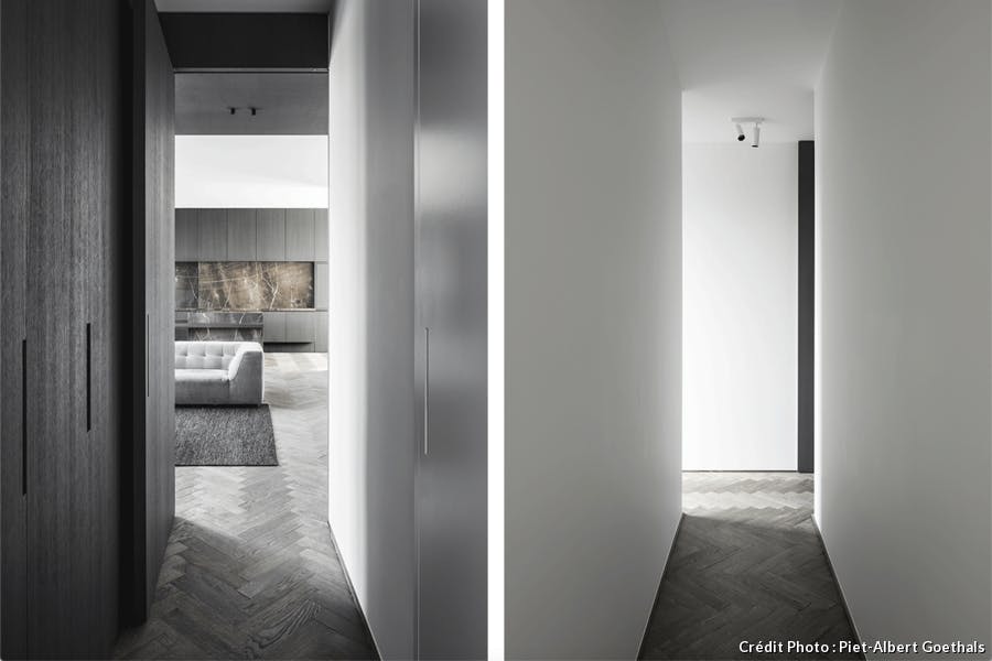 un salon design et contemporain avec un canapé gris et une cuisine en marbre noir et un couloir immaculé