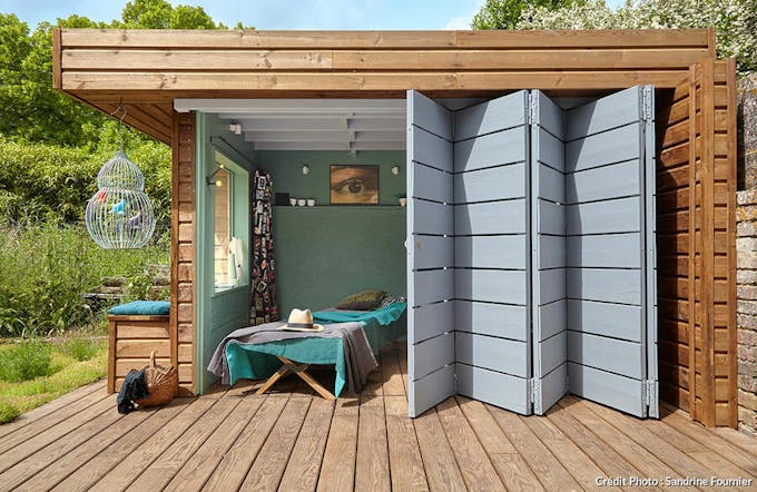 une cabane contemporaine en bois ouverte une terrasse en bois par des portes en accordéon