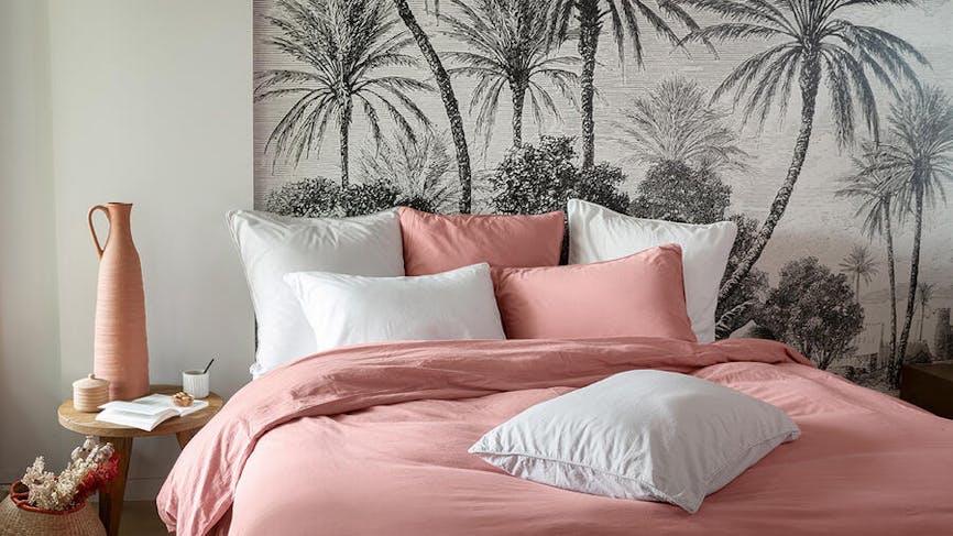 une chambre à coucher avec des draps roses et blanc et un papier peint noir et blanc à palmiers