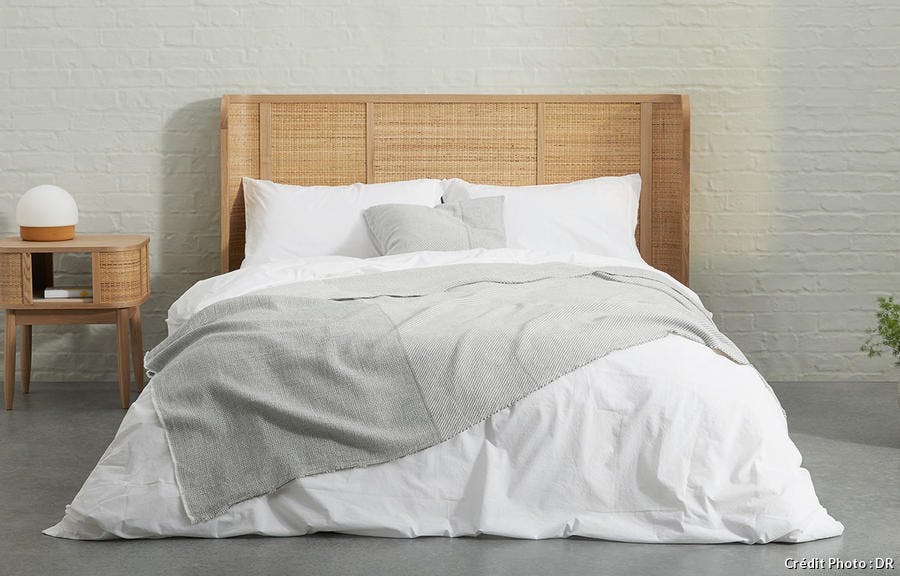 une chambre à coucher moderne avec une tête de lit en rotin et du linge de lit blanc et gris