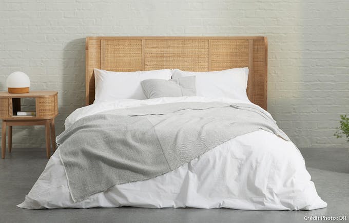 une chambre à coucher moderne avec une tête de lit en rotin et du linge de lit blanc et gris