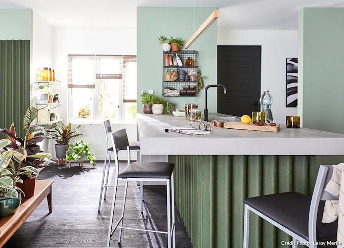 une cuisine vert kaki avec des surfaces en relief et un mur vert d'eau