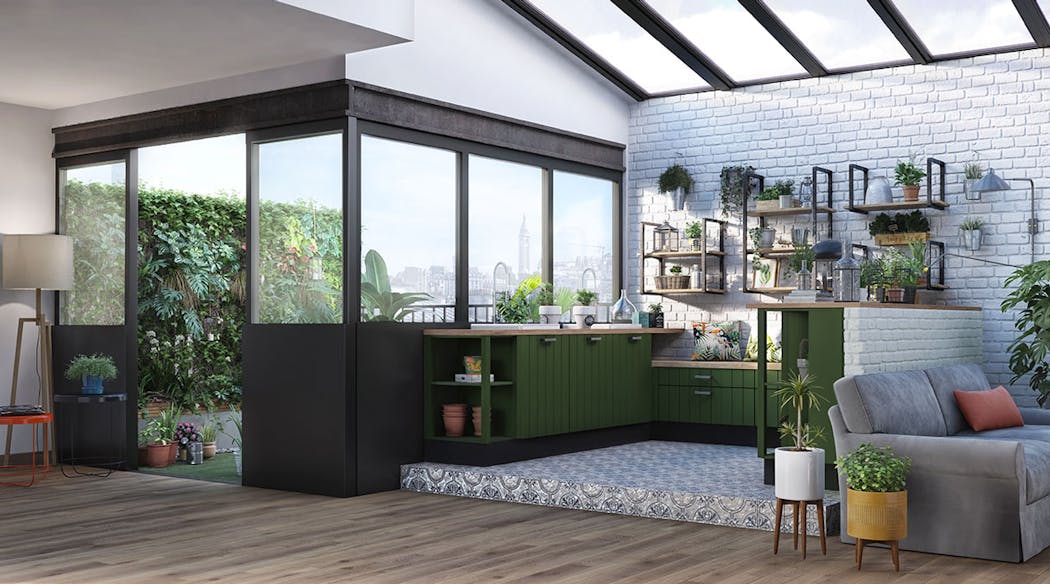 Une cuisine en bois vert dans un loft surplombée d'une verrière et donnant sur une terrasse.