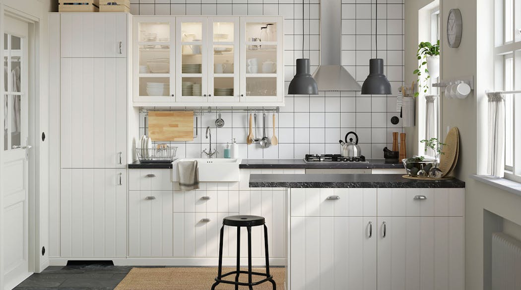 Une cuisine contemporaine en bois blanc avec des portes vitrées et un carrelage blanc souligné par des joints foncés