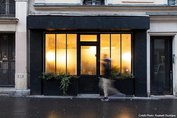 La façade éclairée d'un appartement parisien en rez-de-chaussée sur rue.