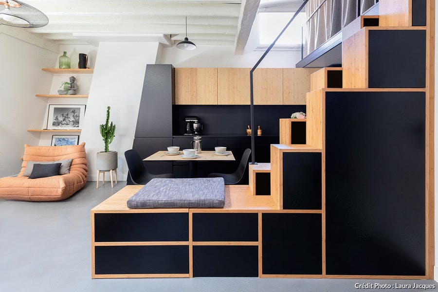 Un studio optimisé grâce à une structure sur mesure en bois faisant office de rangement, de cuisine et d'escalier.