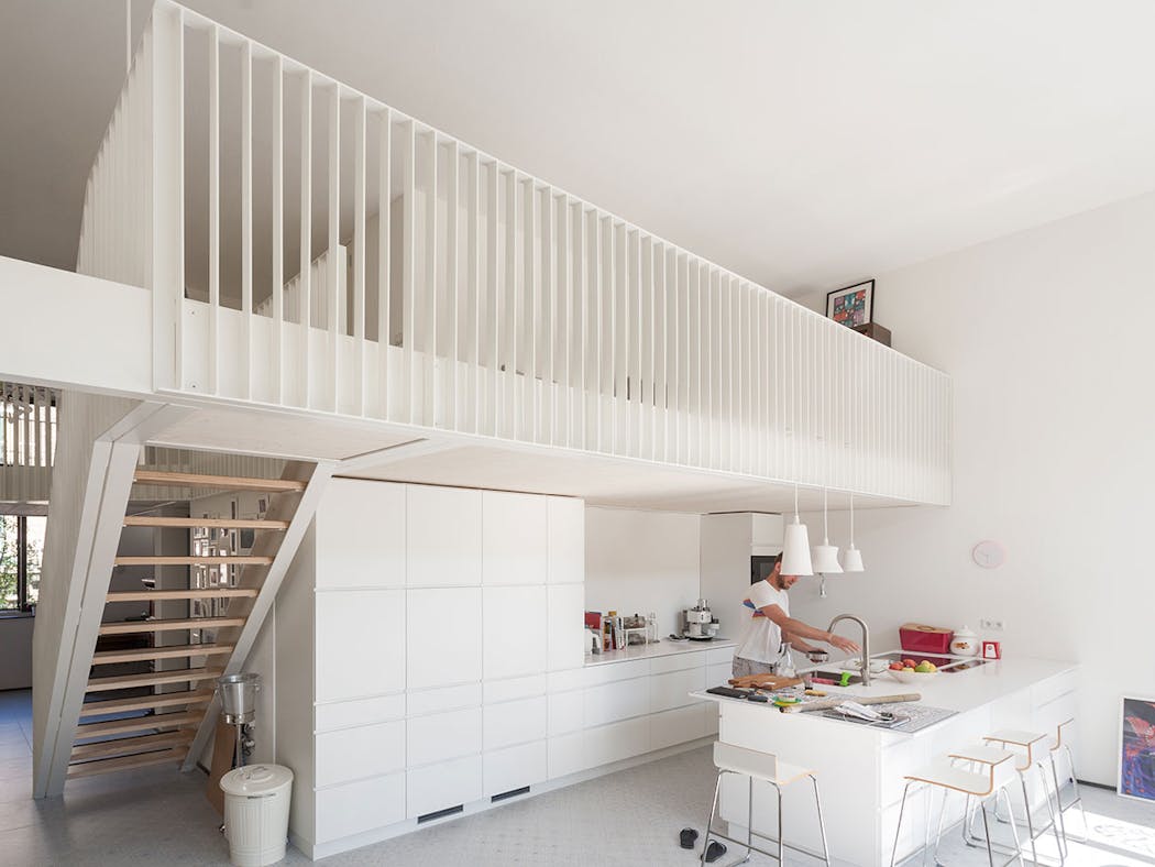 Une mezzanine avec une balustrade immaculée façon claustra dans une cuisine ouverte avec ilot central