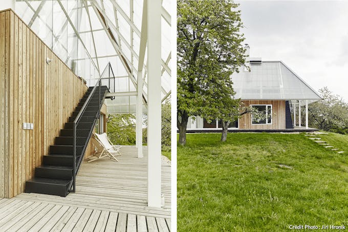une terrasse en mois abritée par un plafond en verre et une maison moderne en bois coiffée d'une serre