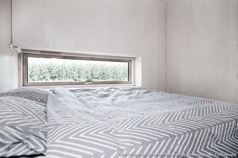 une chambre à coucher entièrement habillé de bois avec une fenêtre panoramique