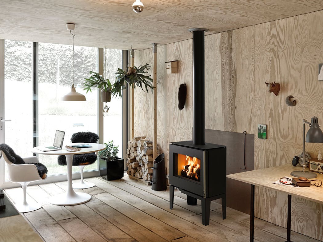 un poêle en métal noir de forme carrée dans une pièce à vivre décorée de style scandinave