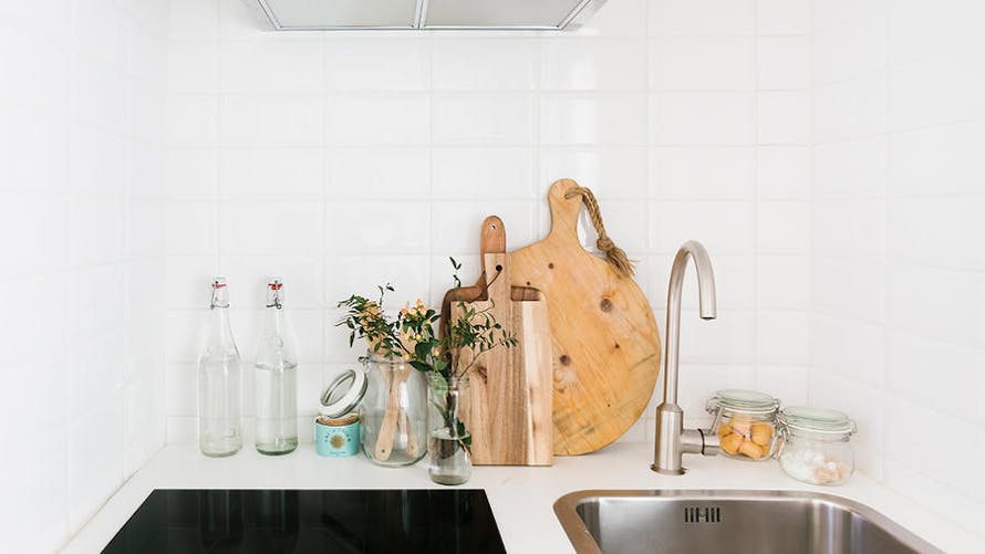 Des bouteilles en verre et des planches à découper en bois sur un plan de travail de cuisine immaculé