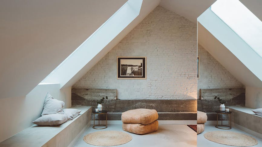 une pièce sous les toits minimaliste avec sole en banquette en béton bruts et mur avec briques apparentes
