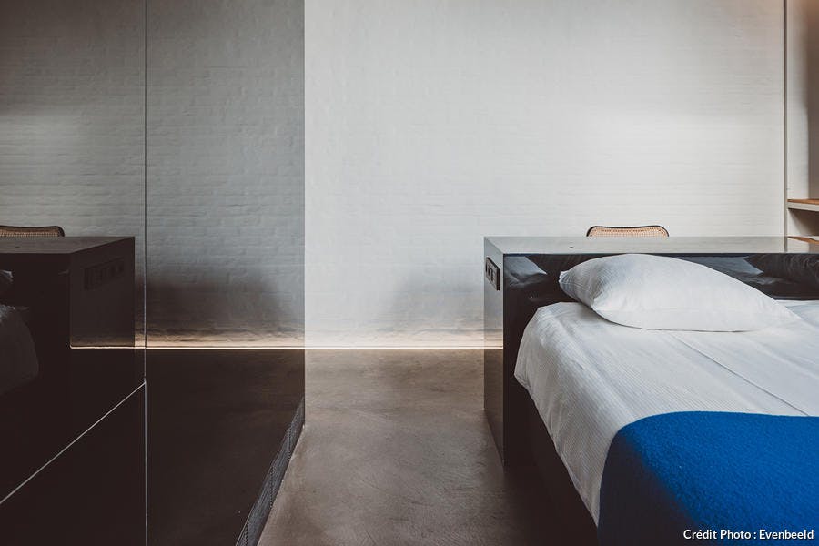 une chambre à coucher avec mur laqué noir et sol en béton ciré