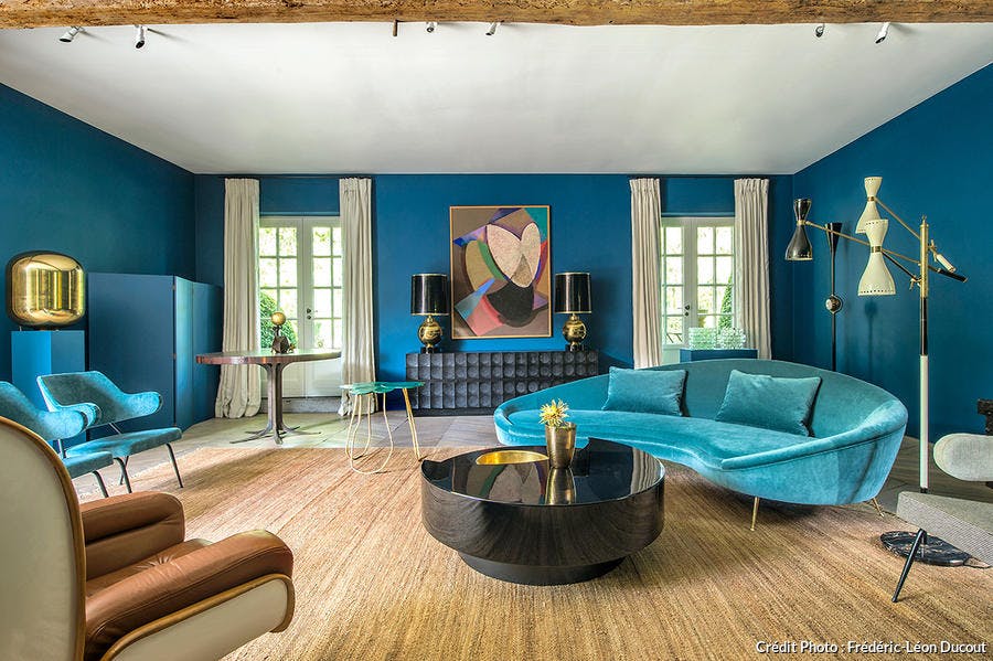 un salon arty avec mobilier vintage, oeuvres d'art et mur bleu.