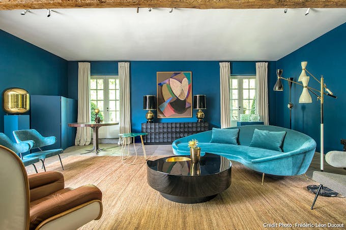 un salon arty avec mobilier vintage, oeuvres d'art et mur bleu.