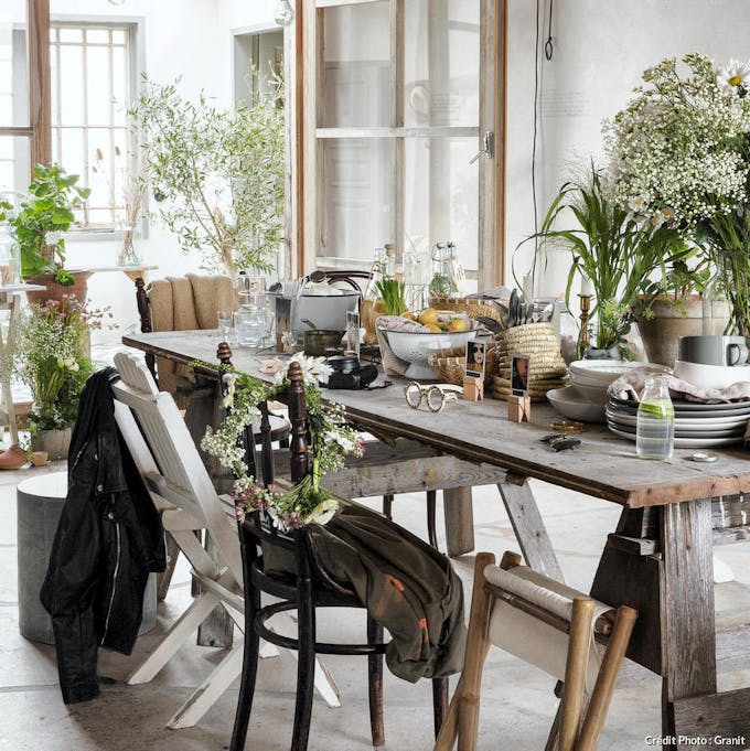 Grande table en bois dans la cuisine avec fleurs et vaisselle