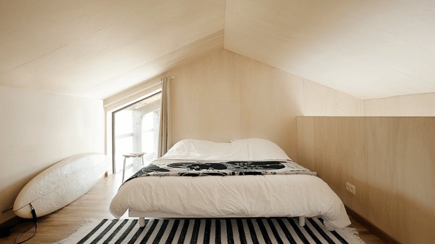 un chambre à coucher minimaliste d'inspiration scandinave avec des revêtements en bois blond et un tapis noir et blanc