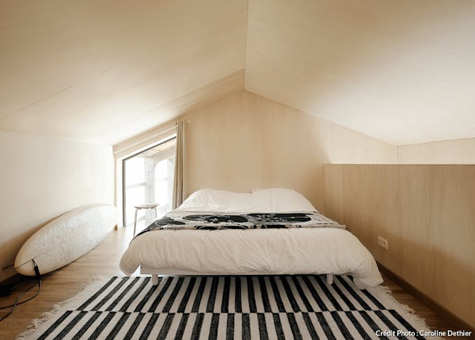 un chambre à coucher minimaliste d'inspiration scandinave avec des revêtements en bois blond et un tapis noir et blanc