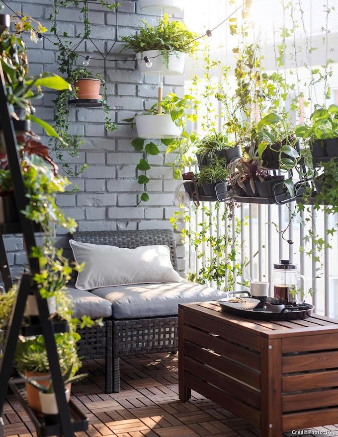 Coffre de jardin en guise de table basse sur un balcon ombragé