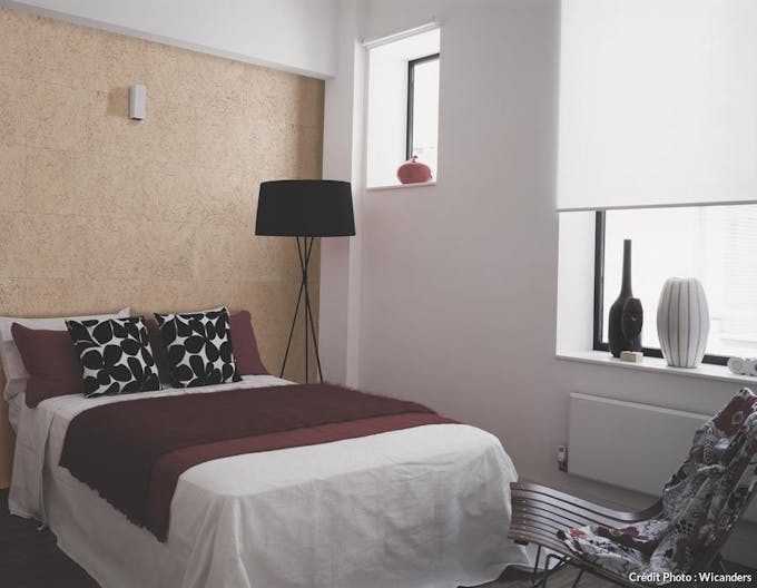 vue d'une chambre avec un lit, un lampadaire et un mur habillé de liège