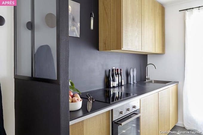 une cuisine en bois avec une verrière et un mur noir