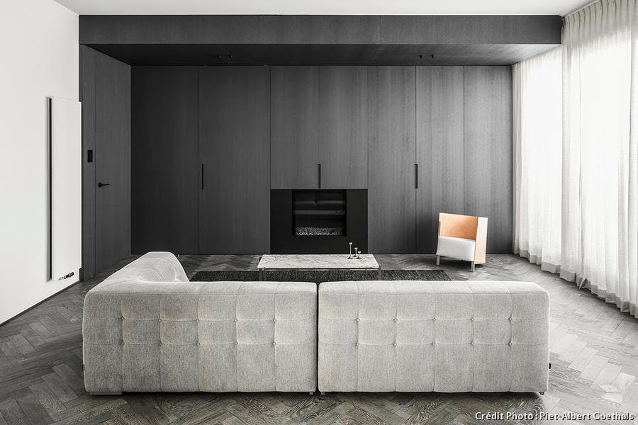 un salon design et épuré avec canapé gris et cheminée intégrée dans un placard sur mesure