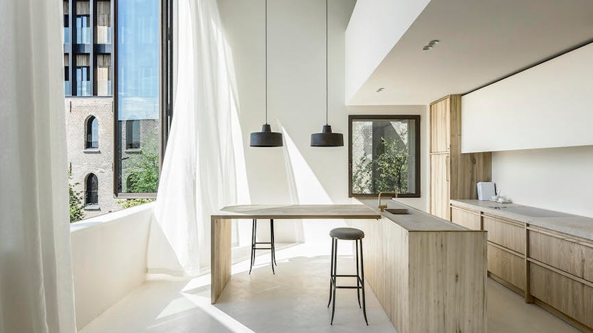 Une cuisine minimaliste en bois clair avec de grandes fenêtres sur l'extérieur